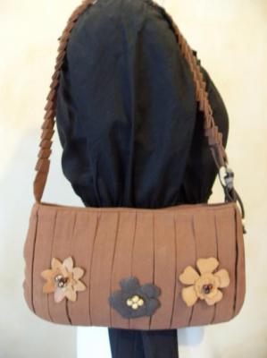 Sac à main marron et fleurs en cuir.