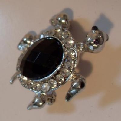 Broche tortue argentée et strass noir.