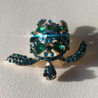 Broche tortue dorée et strass bleu-vert.