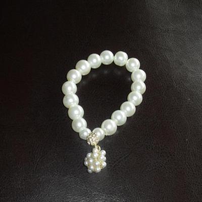 Bracelet blanc, perles de culture, strass blanc et breloque.